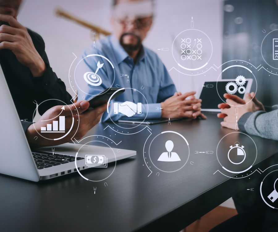 The image shows business professionals at a table with digital icons representing data analytics, collaboration, finance, and productivity tools.