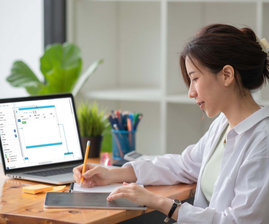 Image depicting seated woman planning a workflow using the Intelligent Workflow module by Frontier Software on her laptop.