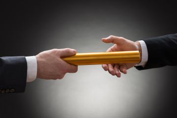 Two business men passing a golden baton to each other