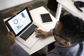 Businessman perusing graphical report on a laptop