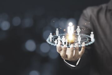 A businessman's hand holding a glowing globe with interconnected human figures