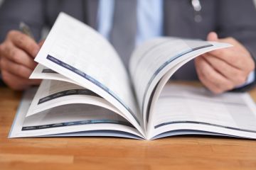 Cropped shot of business man at a desk flicking through a prospectus or brochure