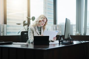 lady working at a computer reading some papers