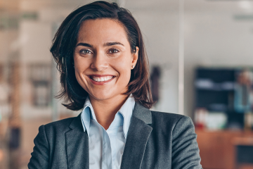 Confident businesswoman in a grey blazer smiling in a modern office environment