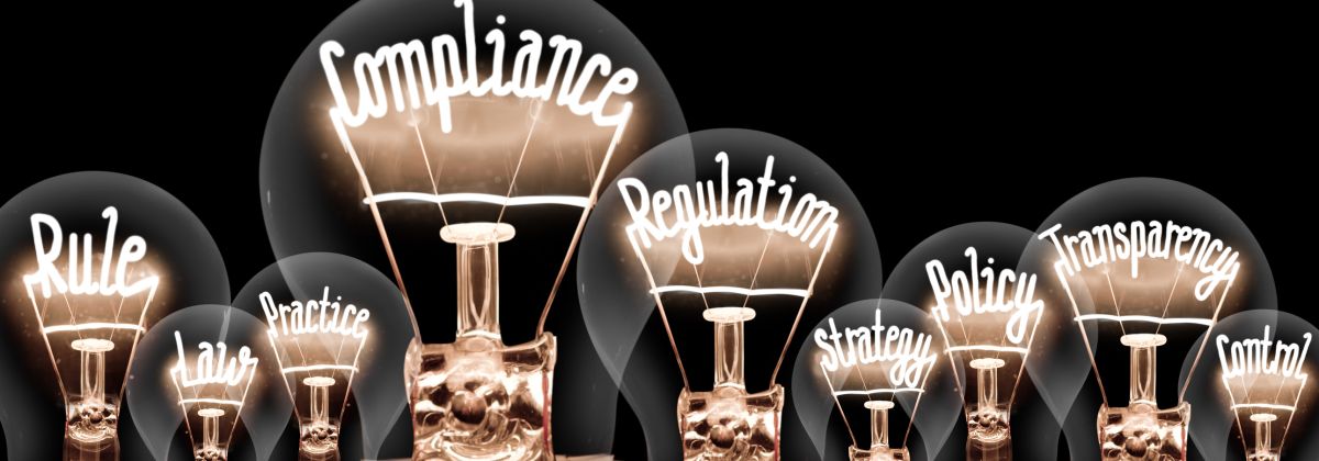 Lightbulbs with words compliance, rule, regulation, policy.